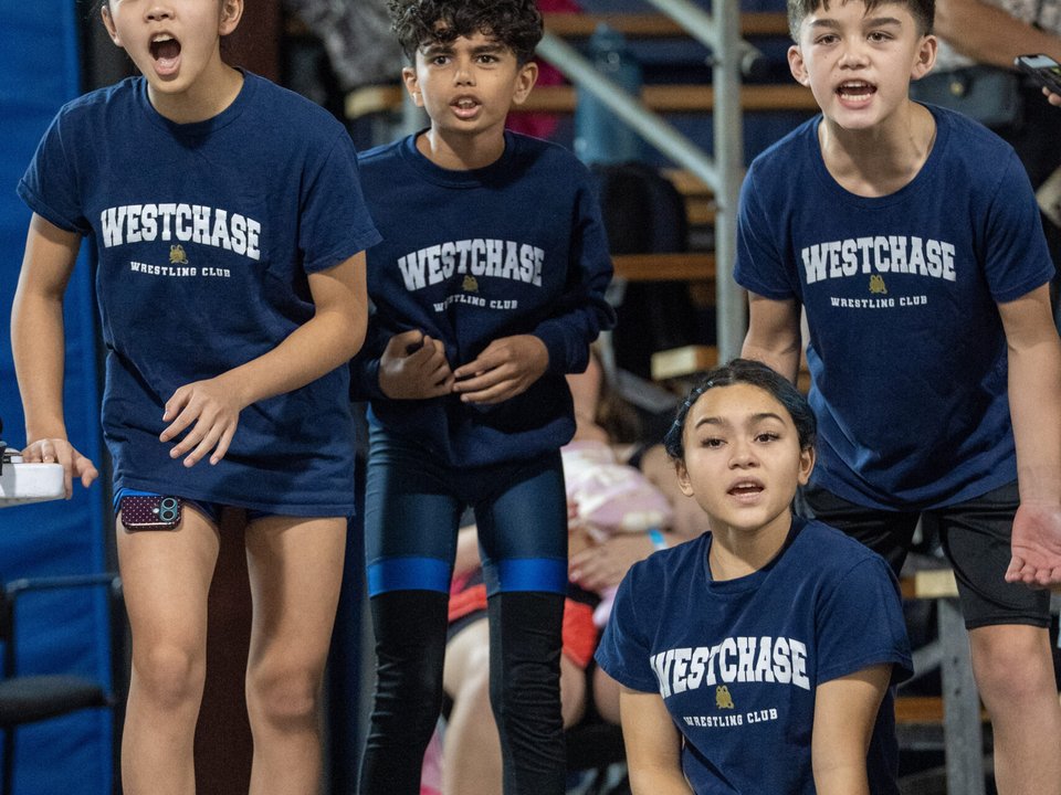 Young Westchase Wrestling teammates cheering beside the mat